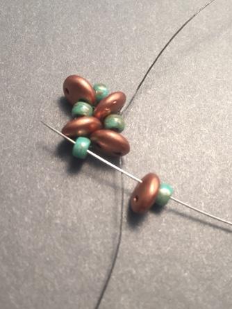Step 8: With the working thread exiting the lentil bead (first bead of the pair), pick up one 8/0 bead and one lentil bead and pass through the 8/0 bead (second bead of the pair).