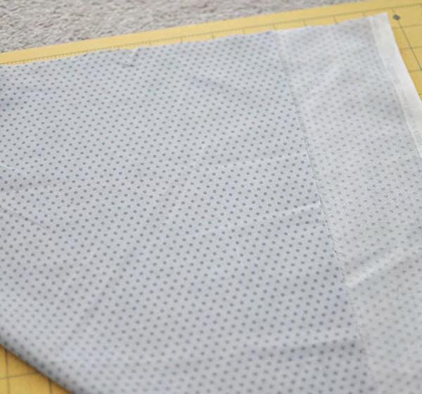 Bring the bottom left corner up to the top right edge. Align the fabric at the top as shown.