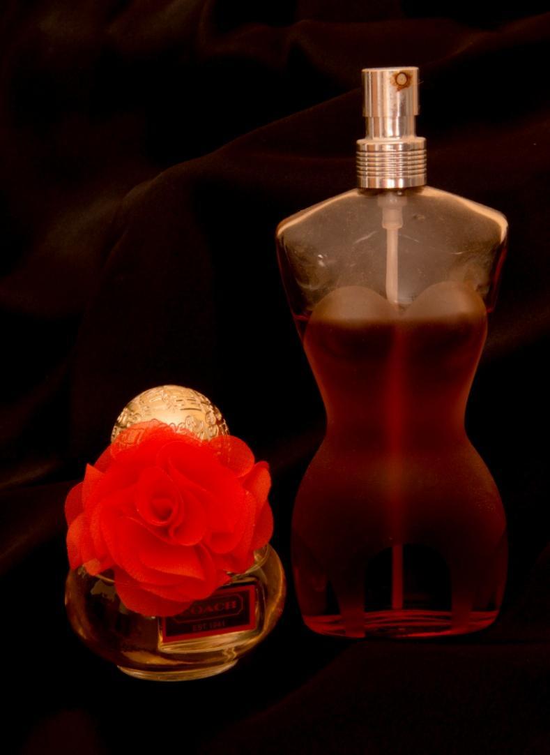 Add a backdrop of black slinky material.. Two perfume bottles.