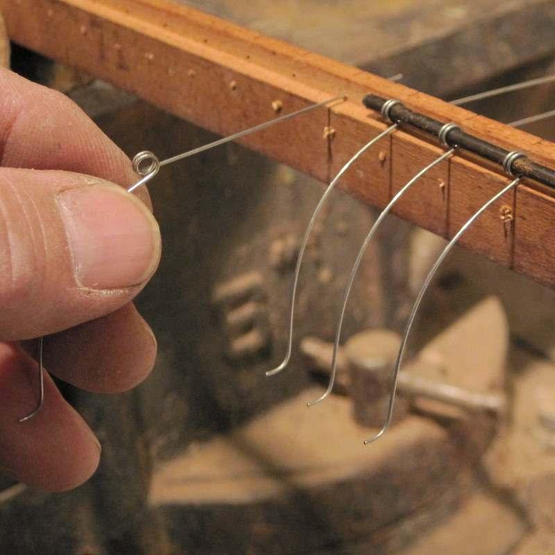 With the coil of the initial spring in the dado slot, push the end of the coat hanger wire through the eye of the coil.