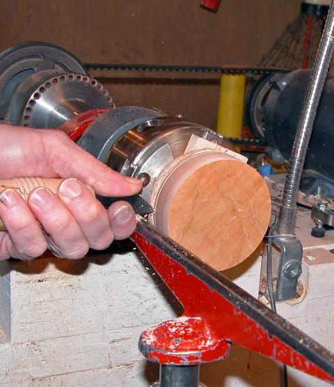 Turn the lathe on and use a bowl gouge to round the edge of the disk.