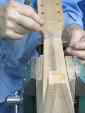 The neck between frets 1 and 10 is carved by making successive cuts at an angle to an existing cut, which makes closer and closer approximations to a conical section the ends of which have radii