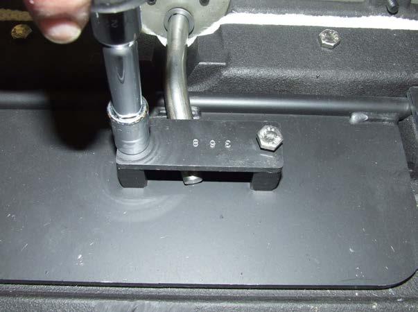 Use a 7/16 socket or wrench to remove the two bolts fastening the steel lift guide plate from the bypass cover.