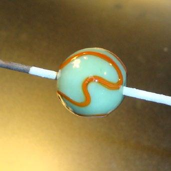 Step 3: Once the base bead is shaped, give it a thorough heating while maintaining the shape. With the vine cane, add a meandering pattern around the bead.