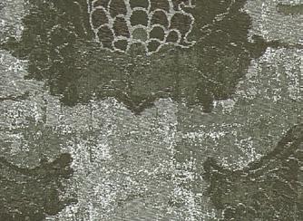The jacquard texture shows medallion-like elements framed by subtle floral contours and a fine patina effect on the ground.