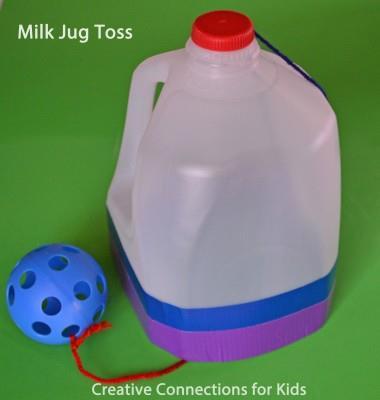 You swing the pom-pom up and catch it in the milk jug. Use your imagination at bit and you will get the gist of it.
