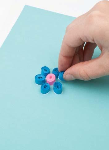 directions (continued) 8 Add petals. Dip one side of some blue rolls in the glue. Place them around the pink roll.