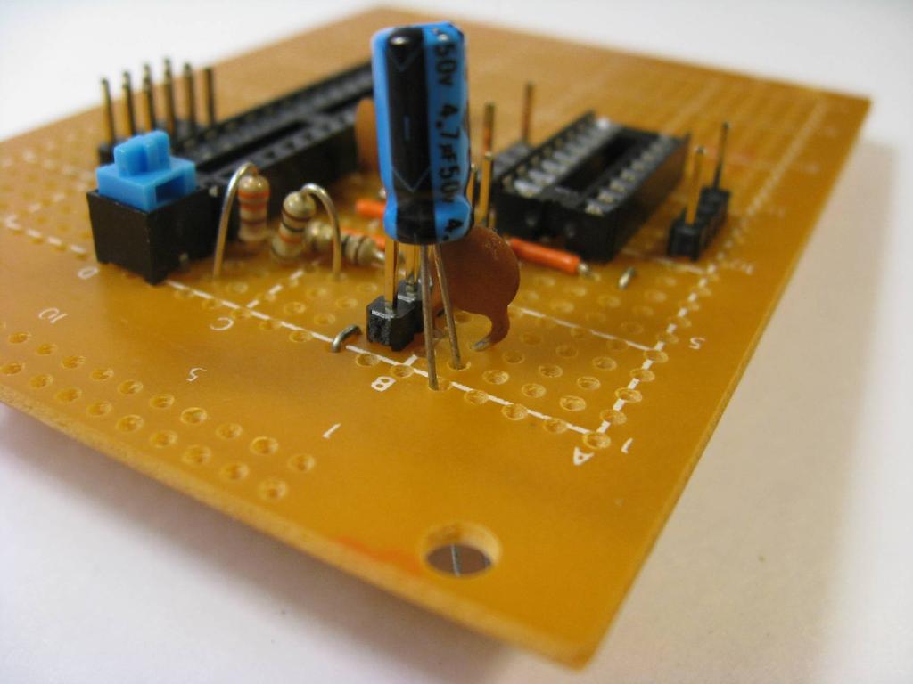 Place a 4.7 μf electrolytic capacitor, a 0.1 μf capacitor (has 104 stamped on it), and a small jumper wire on the board and solder in place.