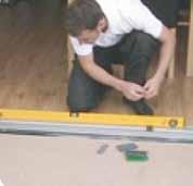 Ensure the track is firm and level in both directions, using a laser level and packers where necessary.