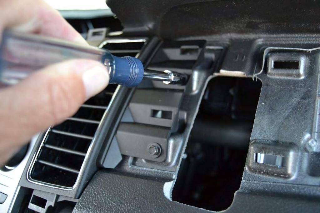 9. Remove the upper and lower bolts holding the center console controls in place next to