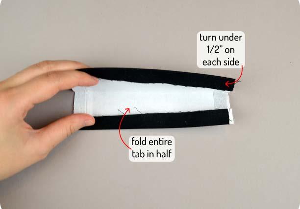 Get out the Buckle Tab back from step 26 and start assembling it. Fold under the long edges by 1/2 and press them in place.