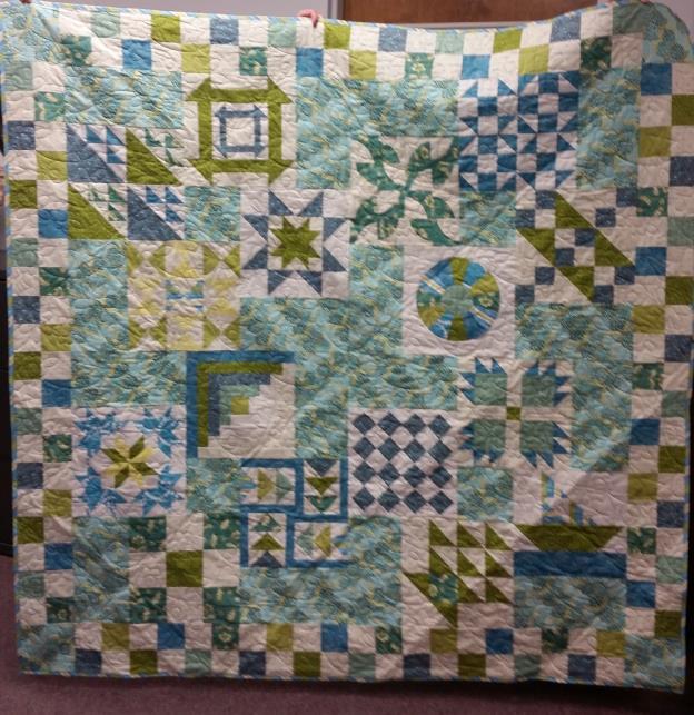 quilt in shades of blues and greens set off with white backgrounds.