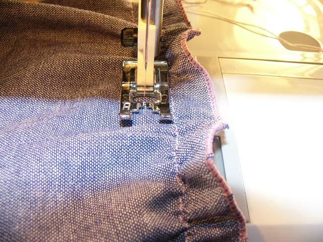 Lining the rolled hem edge of the overalls up at the 5/8 mark on your sewing machine with the right side of the fabric facing up, stitch a straight row from edge to edge of the front of the overalls,