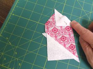 Align the long edges of one of the small triangles with the upper right angled edge of the half heart piece with right sides together.