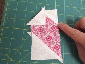 Align another one of the small triangles with the upper left angled edge of the half heart with right sides together.