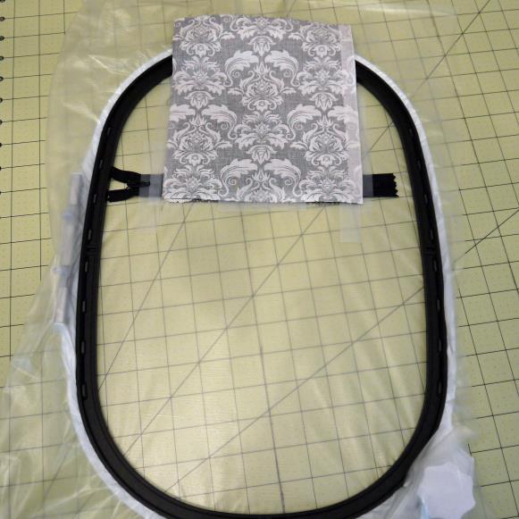 4) Remove the hoop from your machine. Take fabric piece A and place it face down, aligning it with the bottom side of the zipper placement line, covering the zipper, as shown.