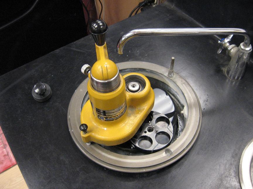 f. Place the Automet over the shaft on the polishing wheel with the Automet turned about 90 degrees counterclockwise from where you