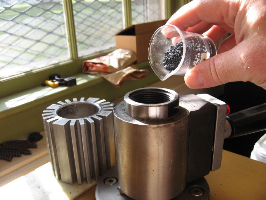 e. Move the Ram Control lever to Down and wait for the piston to move to its lowest position. f. Pour enough black crystal phenolic powder into the cylinder to completely encase the sample plus some extra (typically ~20 ml).