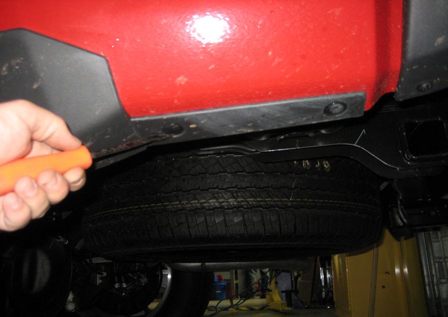 14. Using trim removal tool, remove the 2 plastic rivets on underside of vehicle, behind rear wheel