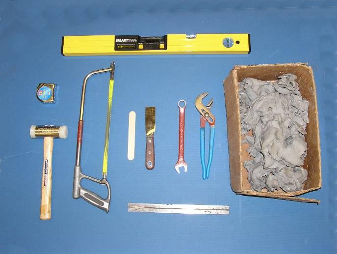 Tools that will be needed are (top) bubble level, (from left to right) tape measure, hammer, hacksaw, popsicle stick, thin scraper,