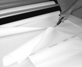 Standing in back of the laminator, lift the laminate up off the liner paper and pull the laminate smooth and taught against the top roller.