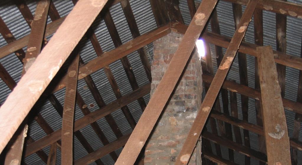 Brick Flue Consists of a brick and mortar chimney suspended from iron brackets set between two extra-thick hewn joists and extending through the roof.