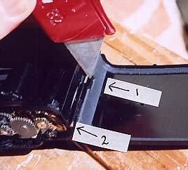Remove the carrying strap, revealing the stainless steel rod (arrow number 1). Using the edge of a small knife, catch the rod and slide it downward.