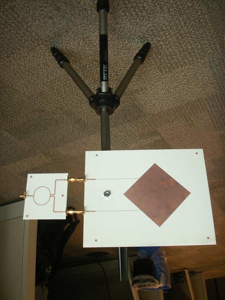 Figure 5: Mounting of the patch antenna with a 2-way Wilkinson power divider attached. The arrows denote the way the antenna is rotated in Section 3.