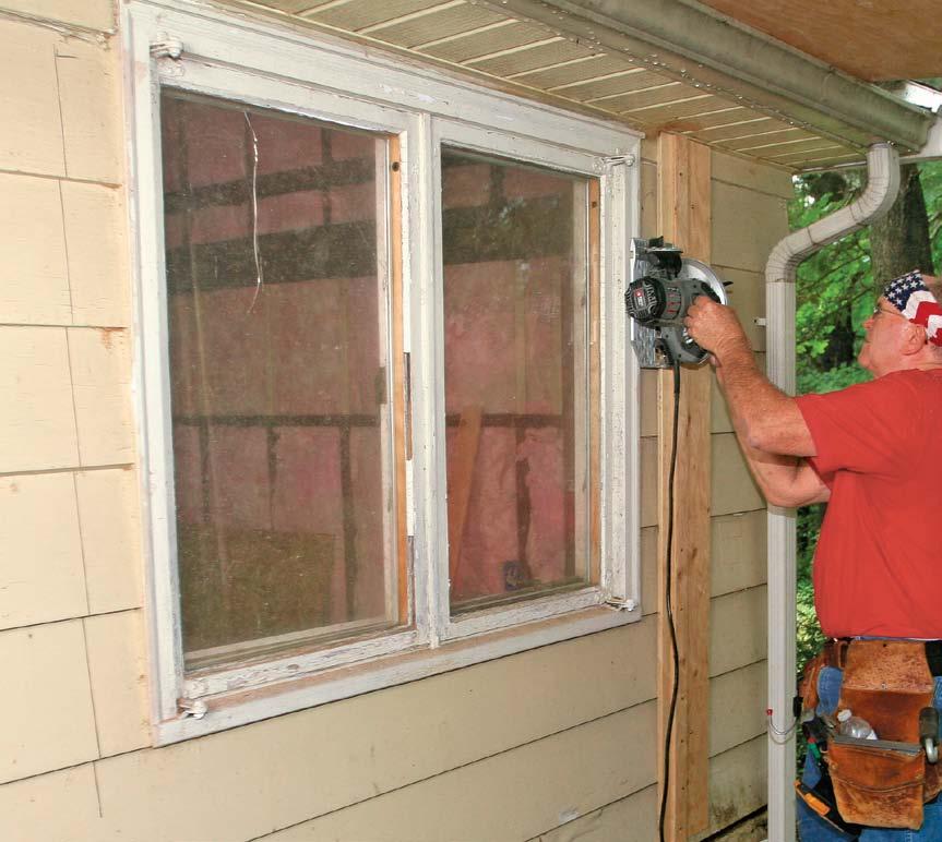 Use a circular saw and a cutting guide (see Building Skills, FHB #6) screwed to the house to cut back the siding around the window.