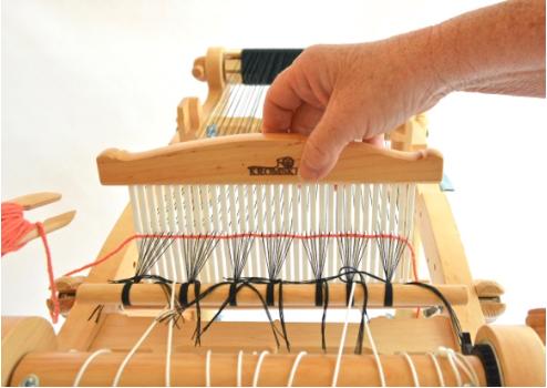 Now take hold of the heddle and gently push the weft down