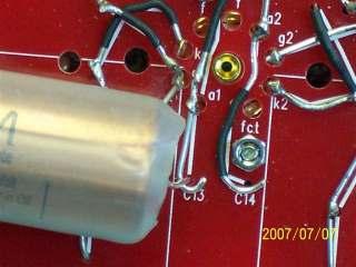 22uf capacitor being inserted into the holes on the board in the C12 position. The line on the capacitor is closest to the spacer or the side of the board.