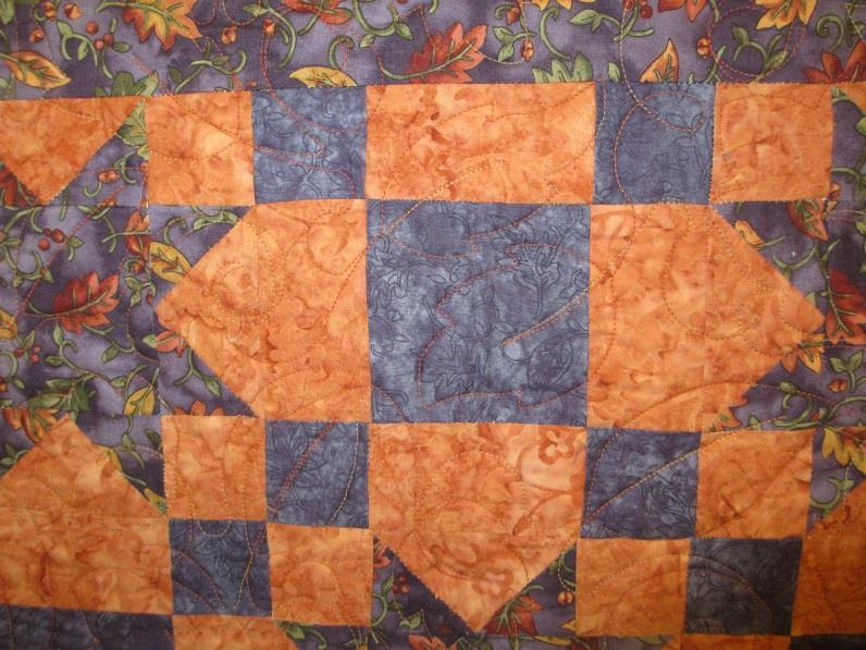 This quilt throw in fall leaf colors highlighted with purple will keep you warm with