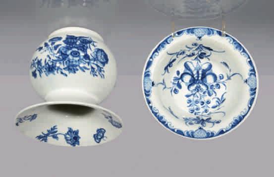 51. A Worcester globular spittoon, printed in underglaze blue with the Three Flowers pattern, the flared rim printed with flowers and a butterfly, 4" high, circa 1768-70, hatched crescent mark 52.