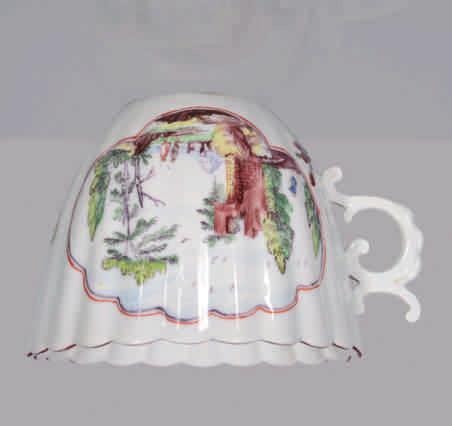 A Chelsea fluted teacup, the C scroll handle with scroll thumbpiece, brilliantly painted in coloured enamels with figures in extensive landscapes, with ruins and trees, within black and iron red