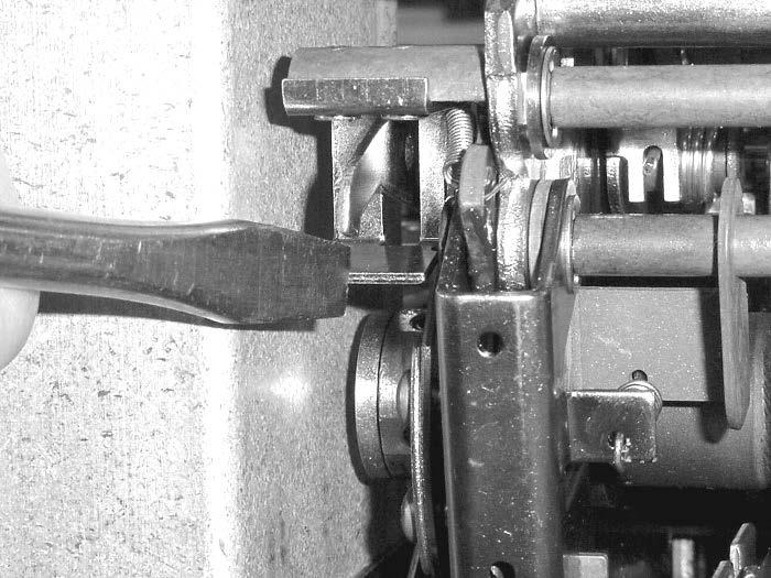 8. Using a screwdriver pull the ratchet arm away from the sprocket to allow for the shaft mechanism to rotate freely (Figure 10).