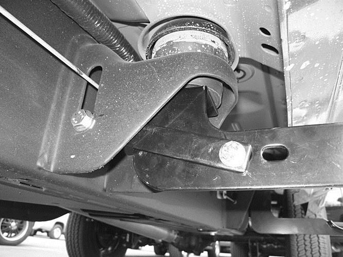 Slide the end of the center support bracket with the larger mounting hole between the factory body mount and the center mount bracket.