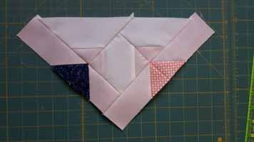 Sew matching units together so that they form an inset triangle. Attach the short side to the appropriate side of the Partial Border triangle.