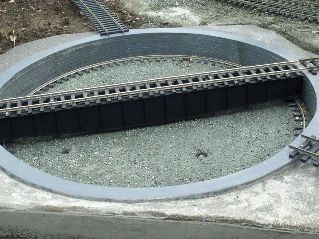 Then cut a piece of track equal to the pit diameter plus ½ and anchor it to the top of the