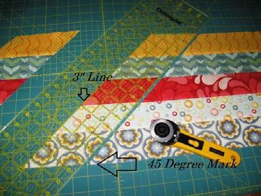 Now line up your 45 degree mark with the bottom of your pieced strips and the 3" line of your ruler with the cut edge of your fabric. Cut.