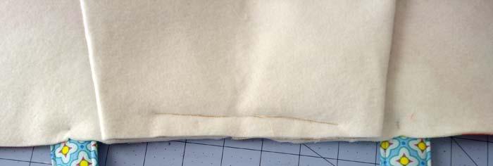 Place the straps upside down on either side of the sewn pleat rough edges