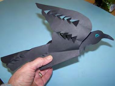 Flip black paper over, keeping fold at the top. Explain to students that they will draw both the flying and landing raven on the same paper, but only one will be cut out.