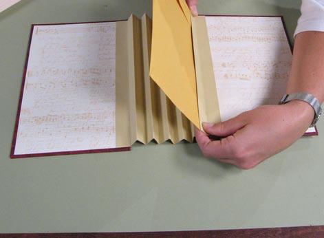 Drop the glued edge down into the last valley fold of the spine, pressing the envelope to the front side of the last spine flap.