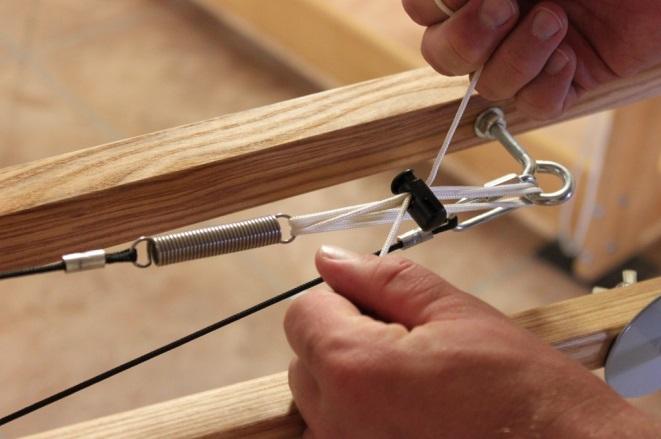 Warping the Sectional Beam bow knot. Wind the rest of the first section on, cut the ends, and secure to the wound on thread using a rubber band over the pegs.
