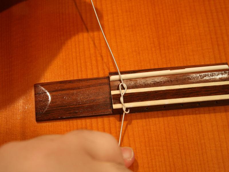 Pass the short end of the string through the loop (2 or 3 times for thick strings, 3 or 4 times for thin strings).
