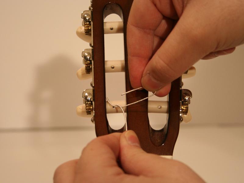 Pull the springy end over the tuning peg and to the left side.