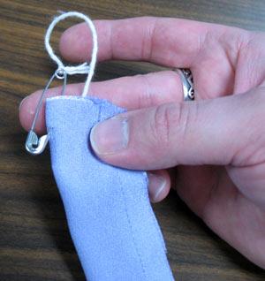 Cut a length of string a bit longer than the satin, and tie the string to a safety pin.
