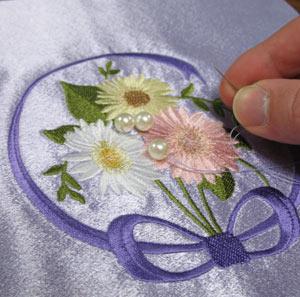 Add a few beads to the center of the embroidered front cover piece.