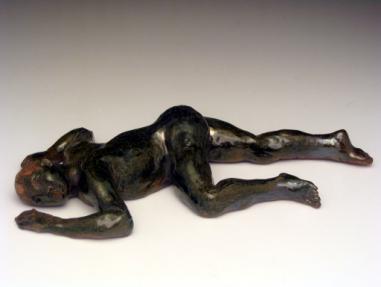 25in) $95 65R Exhaustion I Reclining Male figure, dark greenish glaze, lying on stomach,