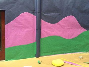 out mountains from a large purple paper roll and attach to the blue wall with spray adhesive.