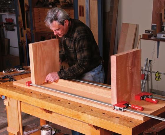 A piece of melamine cut to the exact length of the stretcher serves as a spacer as Cullen uses the doweling jig to drill
